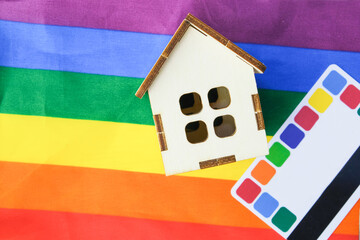 credit card and a small wooden house on the flag of the lgbt community, purchase of suburban real estate by same-sex couples