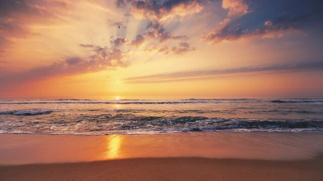 Tropical sea sunrise. Burning sky and shining golden waves splashing on the beach. 