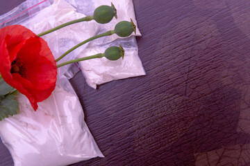 flowers and opium poppy heads next to packages of heroin, soft focus, toning