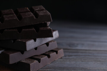 Tasty dark chocolate bars on wooden table. Space for text