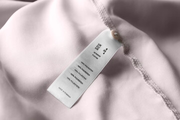 Clothing label with size and content information on light garment, closeup