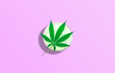 CBD Cosmetic lotion gel and Cannabis leaf isolated on pink