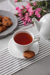 Cup of aromatic tea and tasty cookies on grey table