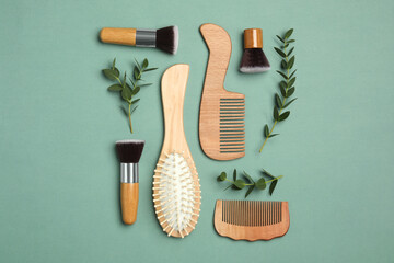 Flat lay composition with modern hair combs and brush on green background