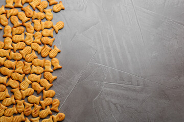 Delicious goldfish crackers on grey table, flat lay. Space for text