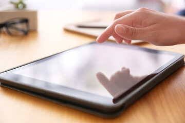 Woman working with modern tablet at wooden table, closeup