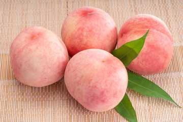 Fresh White Peach fruits with leaves on bamboo mat, Sweet Korean white peach  on wooden bamboo table.