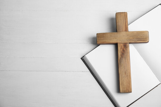 Christian cross and Bible on white wooden background, flat lay with space for text. Religion concept
