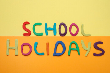Phrase School Holidays made of modeling clay on color background, top view