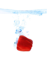Fototapeta na wymiar Red bell pepper falling down into clear water against white background