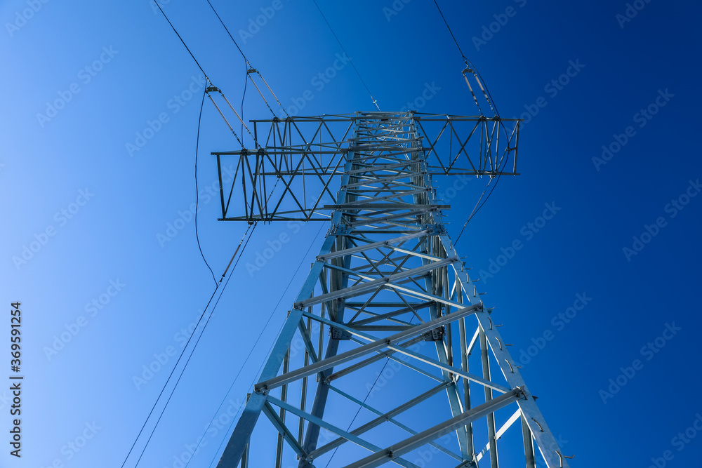 Wall mural modern high voltage tower against blue sky, low angle view