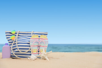 Bag and beach objects on sand near sea, space for text