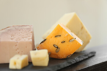 Different types of delicious cheeses on slate plate, closeup