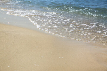 Fototapeta na wymiar Beautiful sea waves on sandy beach, closeup