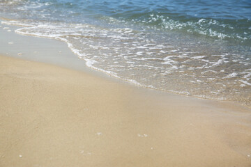 Beautiful sea waves on sandy beach, closeup