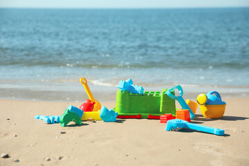 Different child plastic toys on sandy beach. Space for text