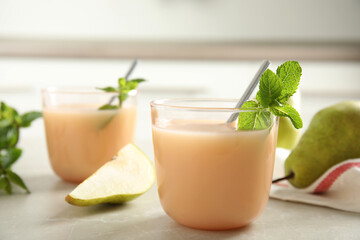 Obraz na płótnie Canvas Tasty pear juice with mint on light grey table, closeup