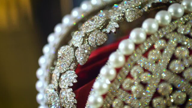 A close view of a sparkling diamond diadem on a red pillow.