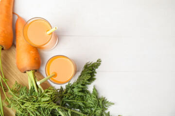 Freshly made carrot juice on white wooden table, flat lay. Space for text
