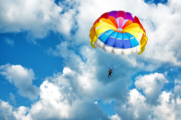 Paragliding using a parachute on background of blue cloudy sky.