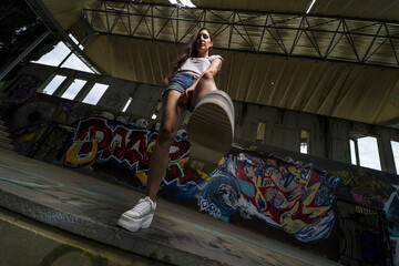 Low angle shot of a young female putting her leg down on the ground in a building with graffitis
