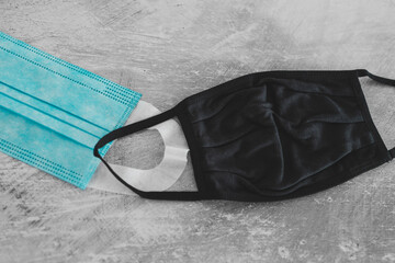 Naklejka premium covid-19 prevention concept, different face masks including surgical mask, fabric and construction ones on concrete surface