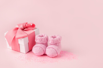 Pair of small pink baby socks and gift box on pink background with copy space for your warm message, baby shower, first newborn party background, copy space, monochrome