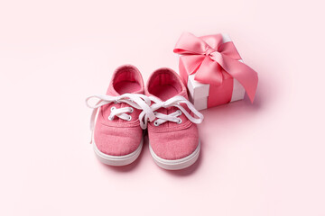 Pink baby shoes and gift present box, concept of first steps, birthday, baby shower, expectation, pregnancy, maternity, motherhood, parenthood. Monochrome card for baby shower party, copy space