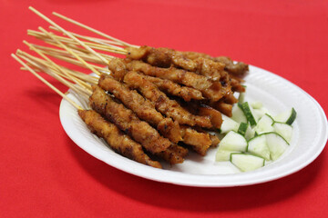 Satay or sate, skewered and grilled meat, served with cucumber. Traditional Malay food in Malaysia, Singapore and Indonesia