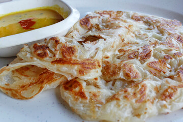 Roti canai or pan fried flatbread consisting of dough, egg, ghee and serve with the curry sauce