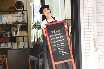 看板を出して開店準備をする女性店員