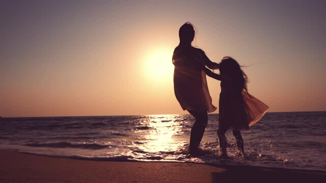 mother and girl playing on beautiful sunrise on the beach