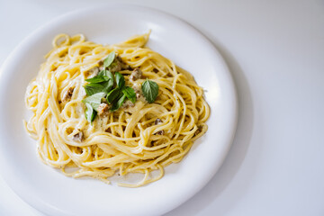 Homemade spaghetti Carbonara with pieces of bacon and basil.
