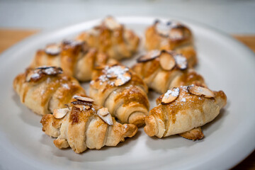 Freshly baked homemade little croissants with almond and sugar powder on a white plate