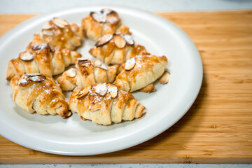Freshly baked homemade little croissants with almond and sugar powder on a white plate