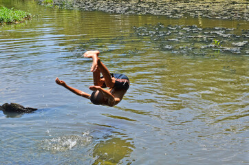 Somersault action of a boy into the water in the canal