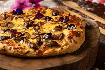 homemade rustic pizza with mozzarella cheese, figs, flowers and brie on wooden table