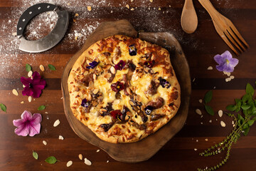 homemade rustic pizza with mozzarella cheese, figs, flowers and brie on wooden table