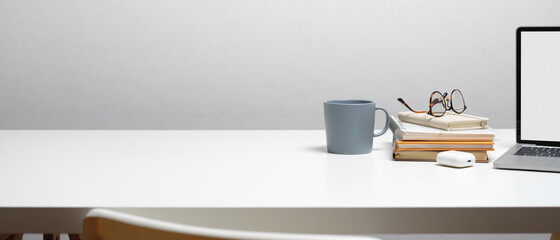 Workspace with books, glasses, mug, clipping path laptop and copy space on white desk