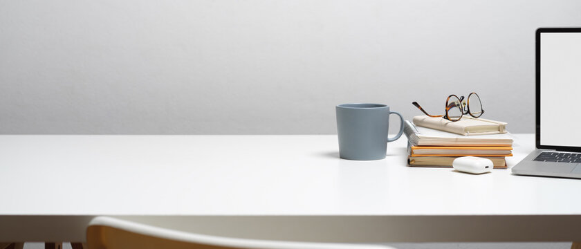 Workspace with books, glasses, mug, clipping path laptop and copy space on white desk