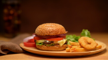 Fresh delicious homemade burger, french fries and onion ring serving on wooden plate