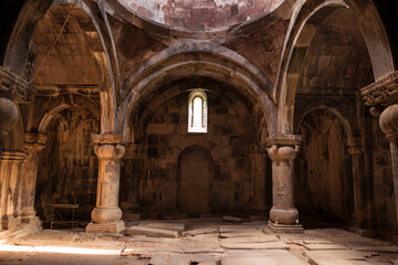 Interior of old Sanahin Armenian Monastery of the Armenian Apostolic Church with ray of light entering through narrow window and headstones on uneven ground