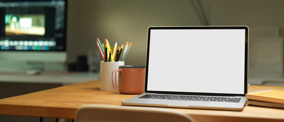 Cropped shot of blank screen laptop on wooden table in office room, clipping path.