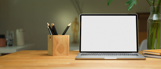 Blank screen laptop on wooden table with stationery and decoration in office room, clipping path.