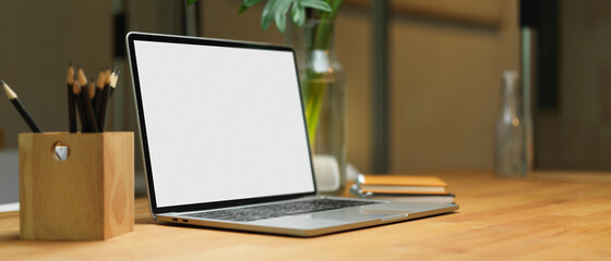 Blank screen laptop on wooden table with stationery and copy space in office room, clipping path.