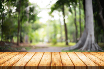 Empty wooden desk space and blurry background of garden or park for product display montage.