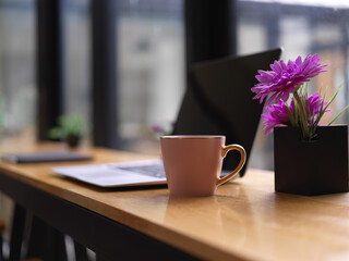 Side view of portable workspace with laptop, beverage cup and flower vase on bar in cafe