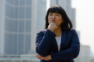 Fototapeta premium Young beautiful overweight Asian businesswoman against view of the city