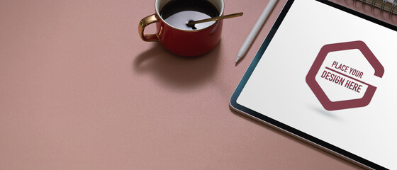 Workspace with mock up tablet, stylus, coffee cup and copy space on pink table