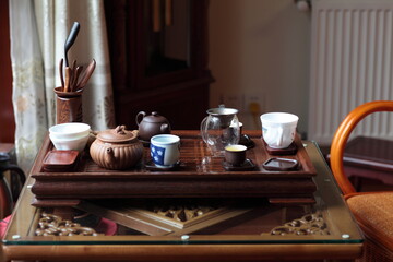View of Traditional Chinese style tea set with Purple Clay Pots, tea cups and tea tools in a solid hardwood tea tray on table